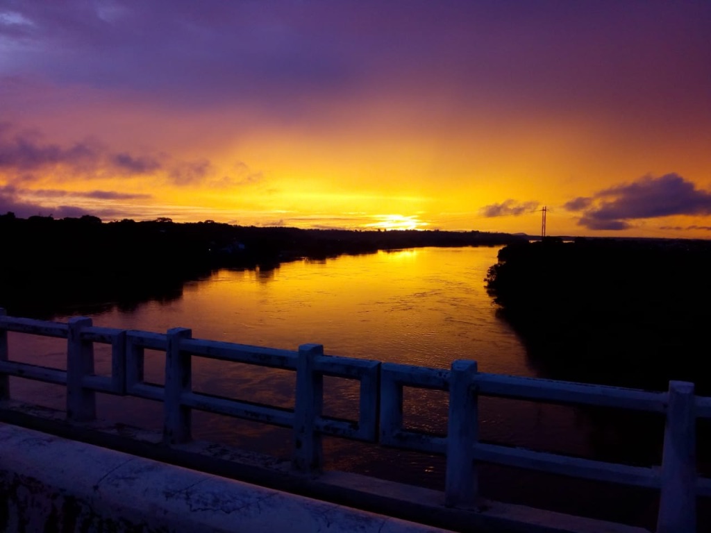 Pôr do Sol vista no rio Itacaiúnas com cores misturadas de amarelo, vermelho, laranja, lilás e roxo.